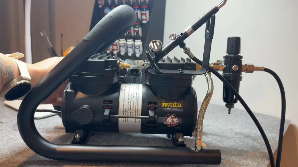 Her airbrush compressor and airbrush on the desk, Episode 01