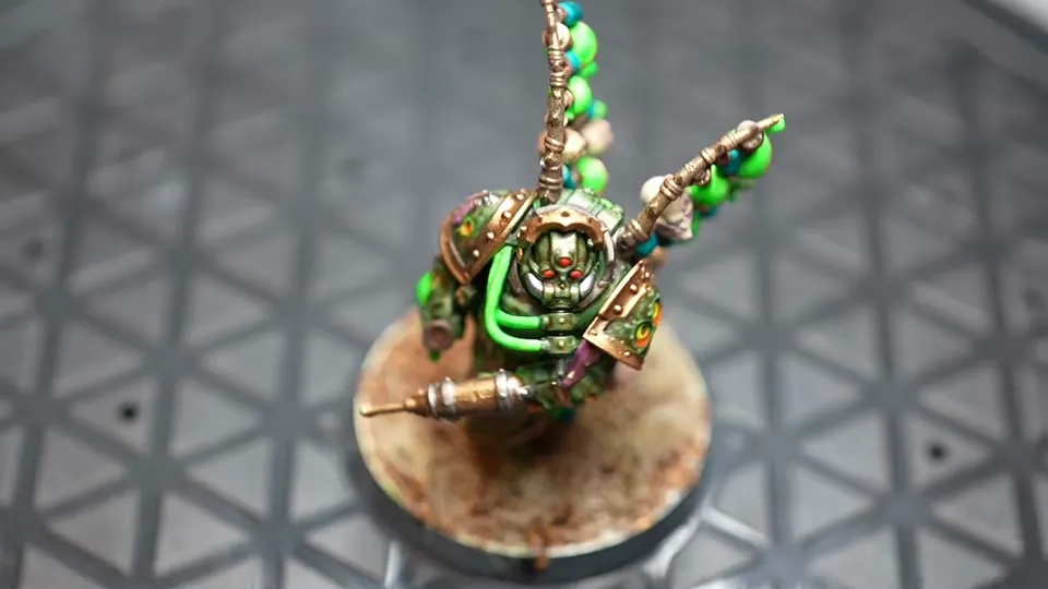 Her finished Biologus Putrifier miniature on its base, green armour and glowing vials, Episode 02